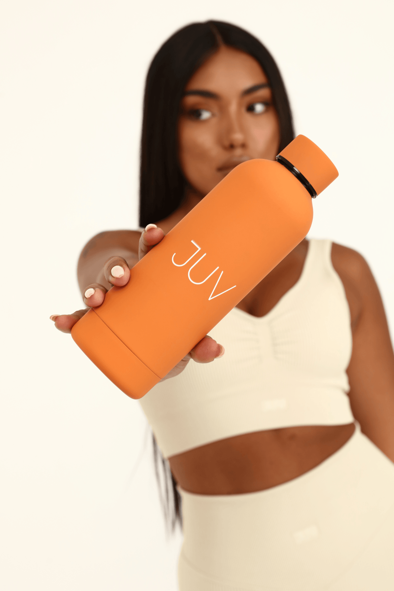JUV mia thermal bottle in orange, front view in the model hands.
